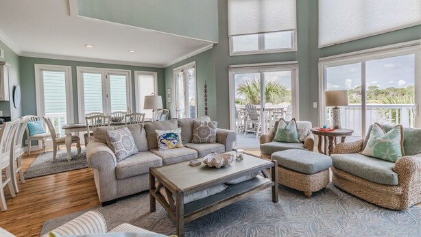 A spacious living room with a high ceiling, large windows, and a view of the outdoors. - Golf and Ocean Views, 6 seat golf cart included (Fripp Island)