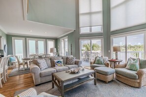 A spacious living room with a high ceiling, large windows, and a view of the outdoors. - Golf and Ocean Views, 6 seat golf cart included (Fripp Island)