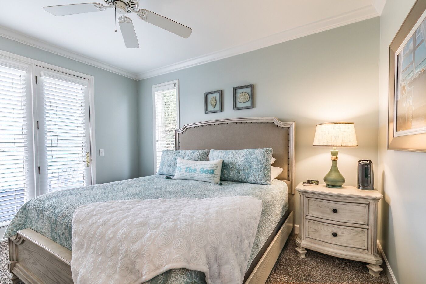 A bedroom with a bed, a nightstand, a lamp, and a ceiling fan.