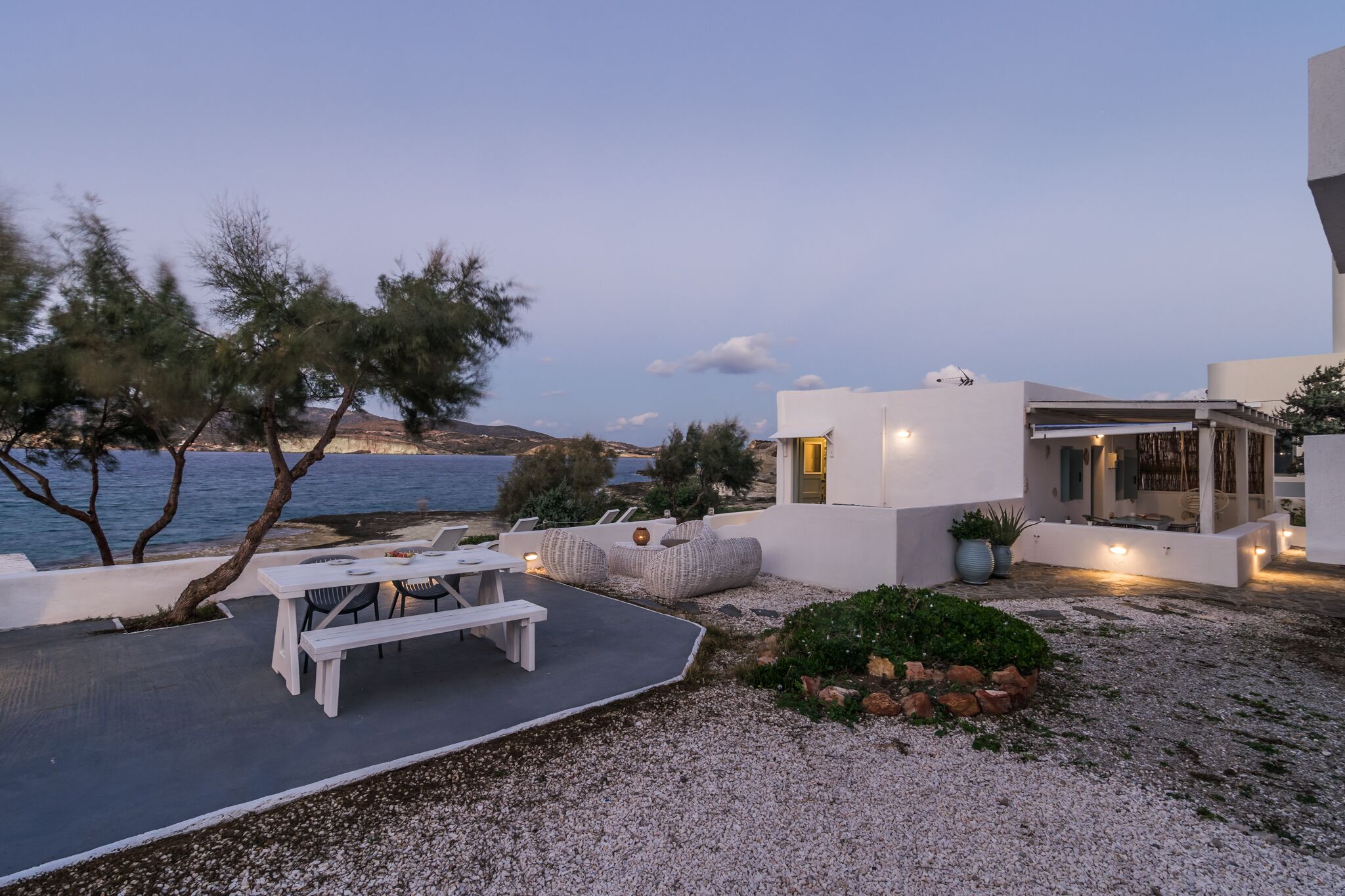 Un patio esterno moderno con zona pranzo, posti a sedere e vista sul mare.