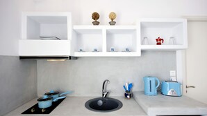 A modern kitchen with a built-in sink, a kettle, a toaster, and a coffee maker on the countertop. - Venia's Guesthouse (Milos)