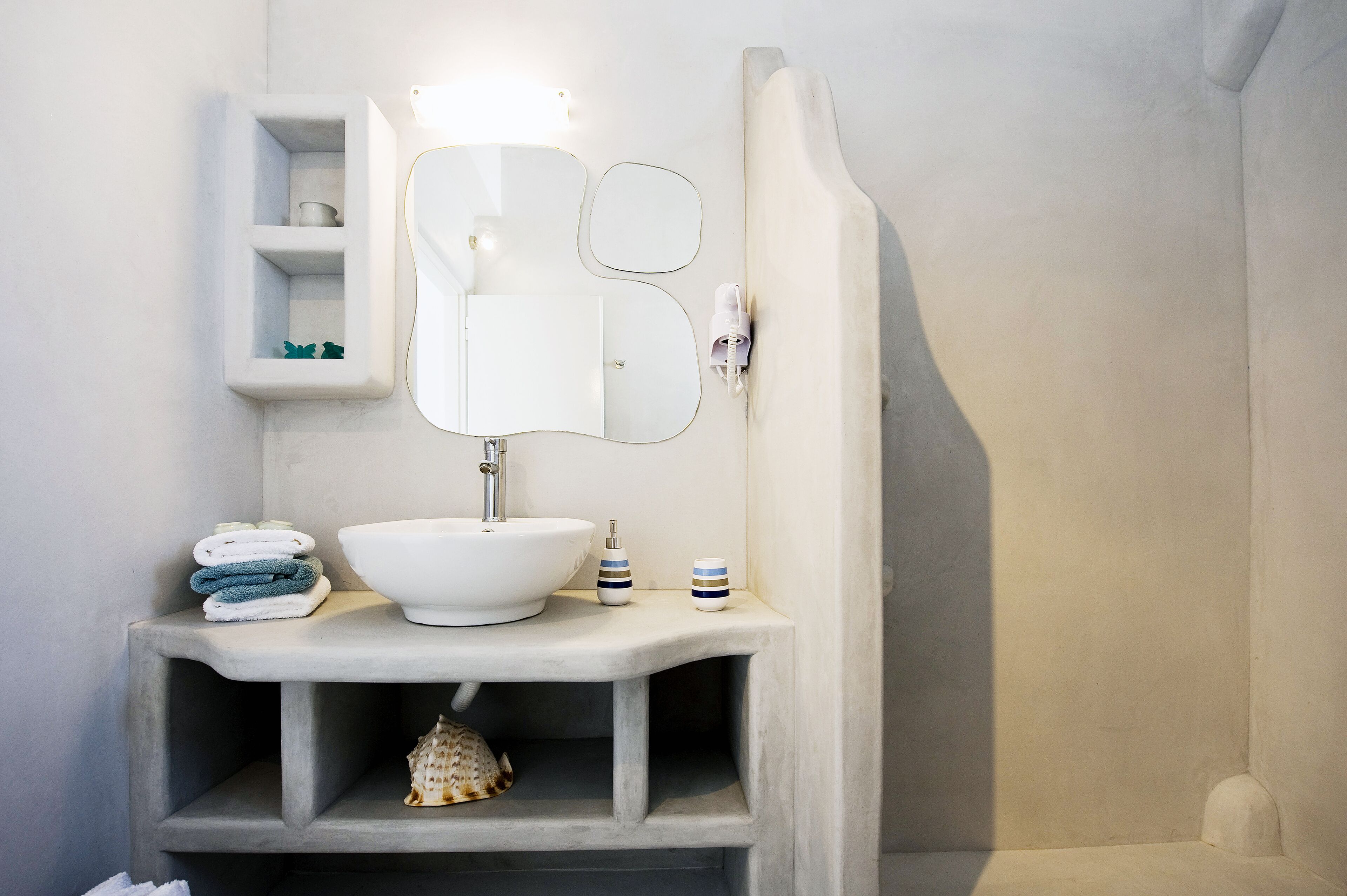 Un baño con un lavamanos blanco, un espejo y un perchero para toallas.