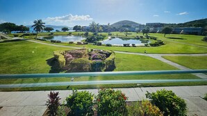 A landscaped garden with multiple ponds, pathways, and a view of a body of water and distant hills.
