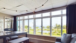 A room with a large window, a desk, a bench, and a sofa.