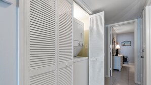 A hallway with a laundry area, a lamp, and a framed picture on the wall.