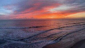 Ein Strand mit Wellen und einem Sonnenuntergang.