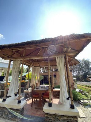 Un espace extérieur aménagé avec une structure en bambou et un sol en pierre.
