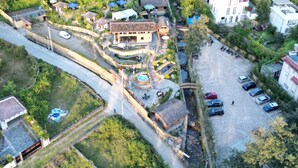 Vue aérienne d’un quartier résidentiel composé d’immeubles de différentes hauteurs, avec un patio central agrémenté d’une fontaine et un parking.