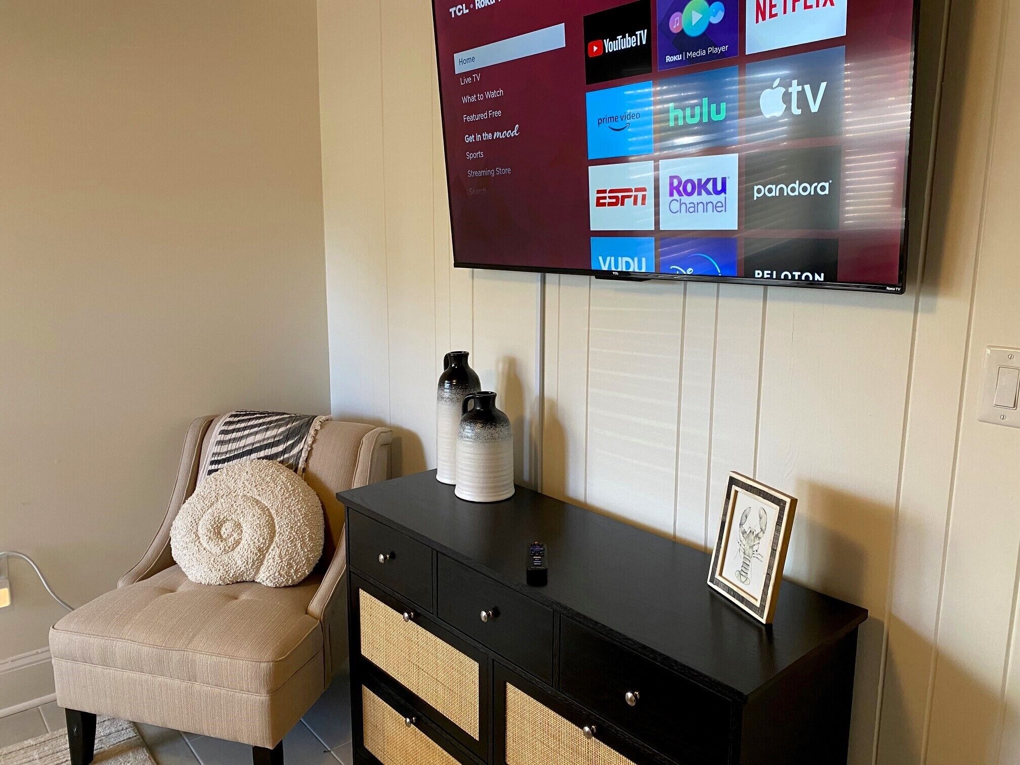 A living room with a flat-screen TV mounted on the wall displaying various streaming services.