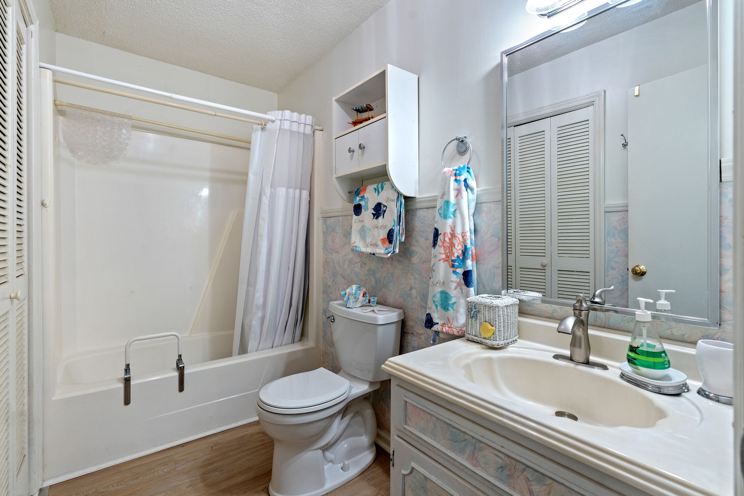 A bathroom with a bathtub, toilet, sink, and mirror.