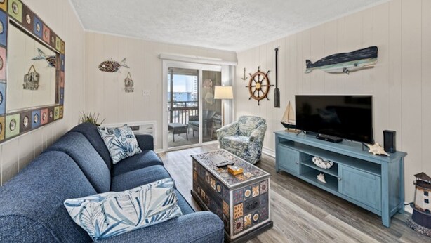 A living room with a sofa, armchair, TV, and a small table.