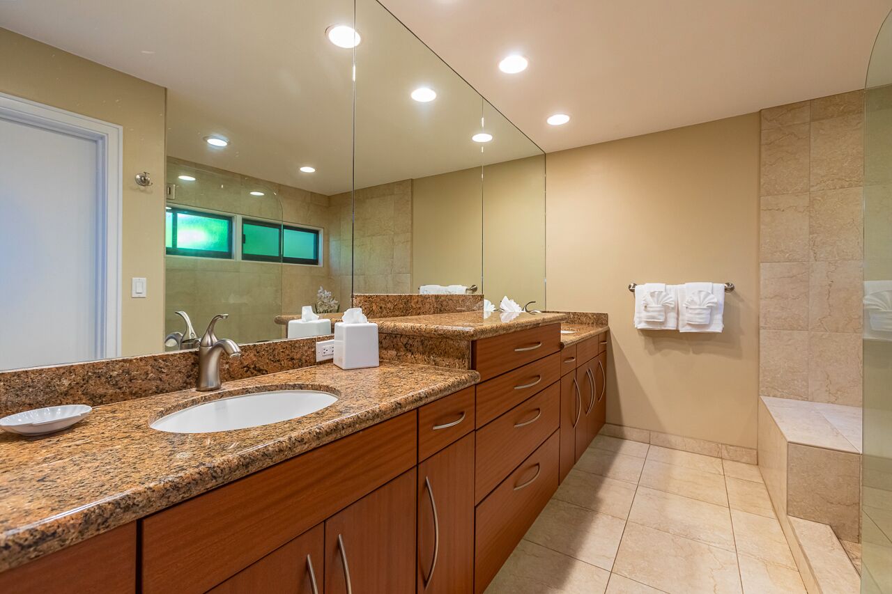 A modern bathroom with a double sink vanity, a large mirror, and a glass shower enclosure.