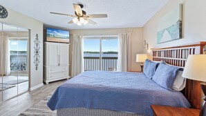 A bedroom with a large bed, a ceiling fan, a TV, a view of the outdoors, and a balcony. - Summer House West C201 (Gulf Shores)