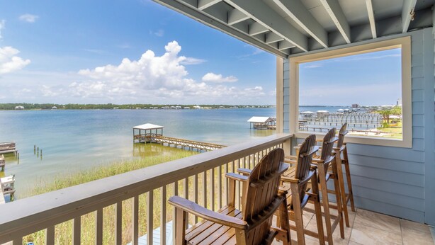 A covered deck with wooden chairs and a view of a lake. - Summer House West C201 (Gulf Shores)