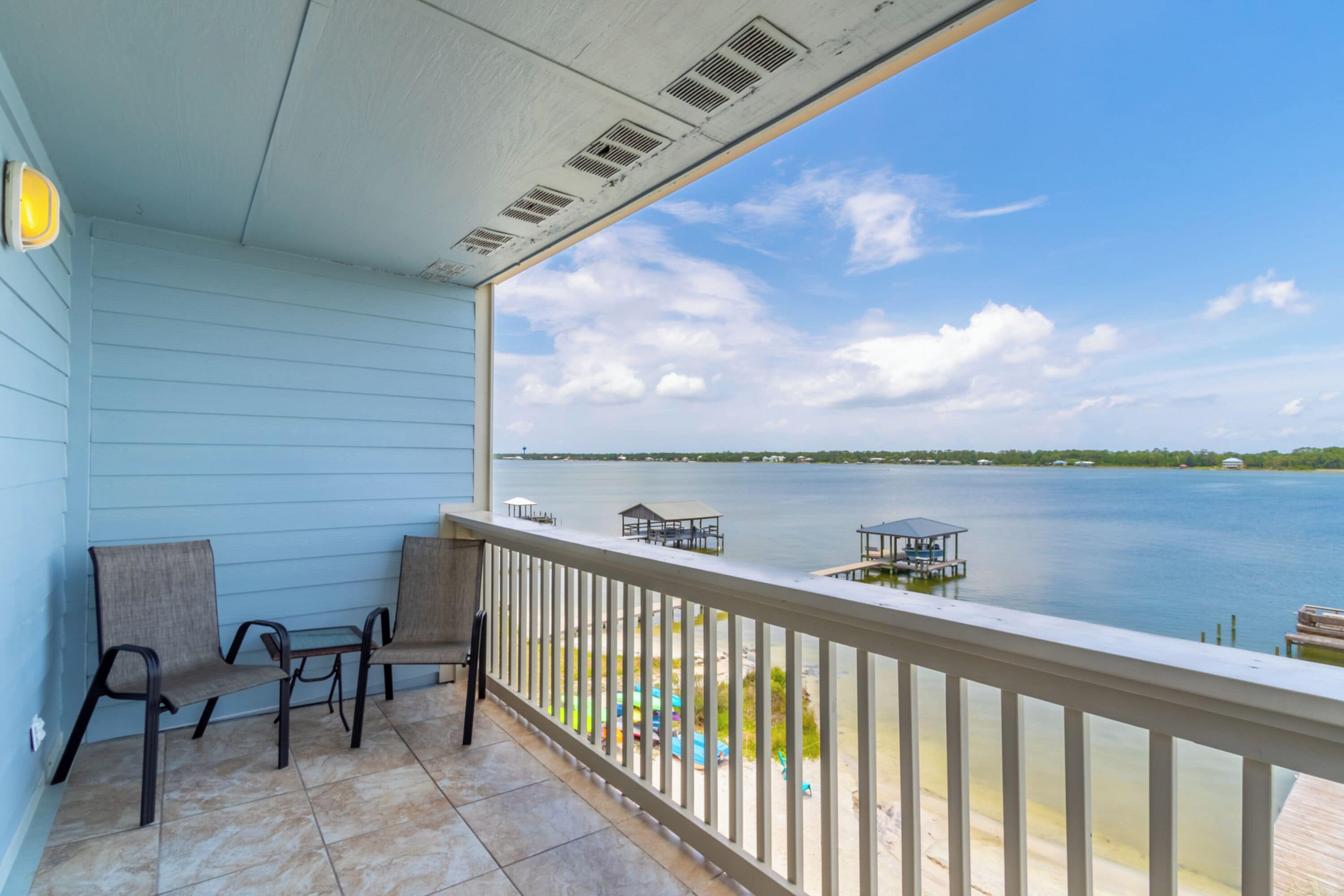 A balcony with a view of a lake, a dock, and a small gazebo.
