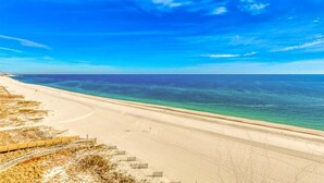 A beach with a wooden boardwalk and steps leading down to the shore. - Summer House West C201 (Gulf Shores)