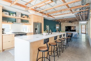 Een moderne keuken met een groot schiereiland, barstoelen en een eethoek met een televisie.