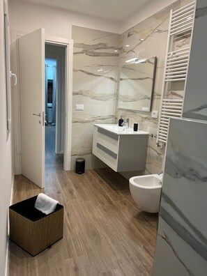 A modern bathroom with a marble backsplash, a freestanding bathtub, and a walk-in shower. - Savoy Apartment (Bari)