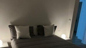 A bedroom with a large bed, two bedside tables, and a nightstand. - Savoy Apartment (Bari)