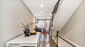 A modern interior with a dining area, a staircase, and a view of the living room.