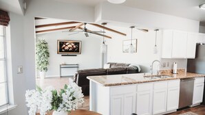A modern kitchen with white cabinets, a granite countertop, and stainless steel appliances.