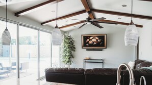 A modern kitchen with a dark leather sofa, granite countertop, and a ceiling fan.