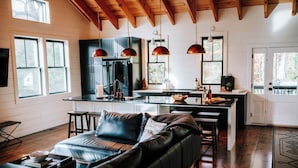 A modern kitchen with dark cabinets, a central island, and pendant lighting. - No Damage One of a Kind Stunning Lodge for 10 Walk Downtown Pool Hot tub  (Clayton)