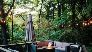 An outdoor deck with a fire feature, seating, and string lights. - No Damage One of a Kind Stunning Lodge for 10 Walk Downtown Pool Hot tub  (Clayton)