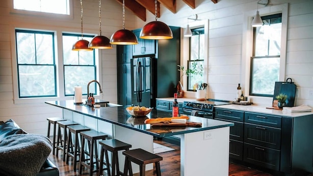 A modern kitchen with a central island, bar stools, pendant lighting, and a view of the outdoors. - No Damage One of a Kind Stunning Lodge for 10 Walk Downtown Pool Hot tub  (Clayton)