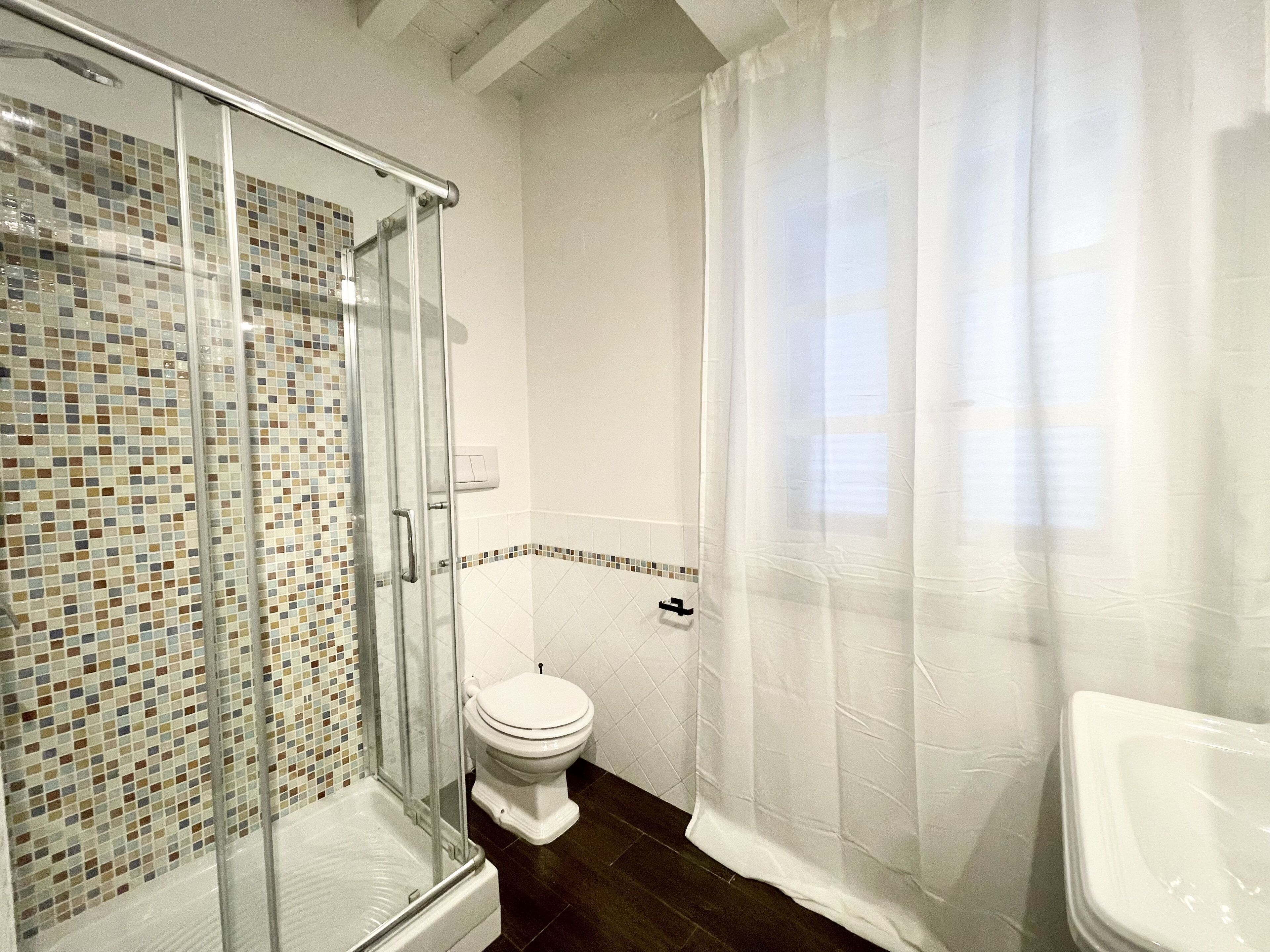 Un baño con ducha de vidrio, inodoro y bañera.