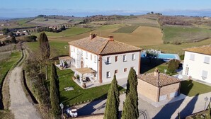 Un grand bâtiment blanc, doté d’un toit recouvert de tuiles, entouré de jardins bien entretenus et d’une piscine.