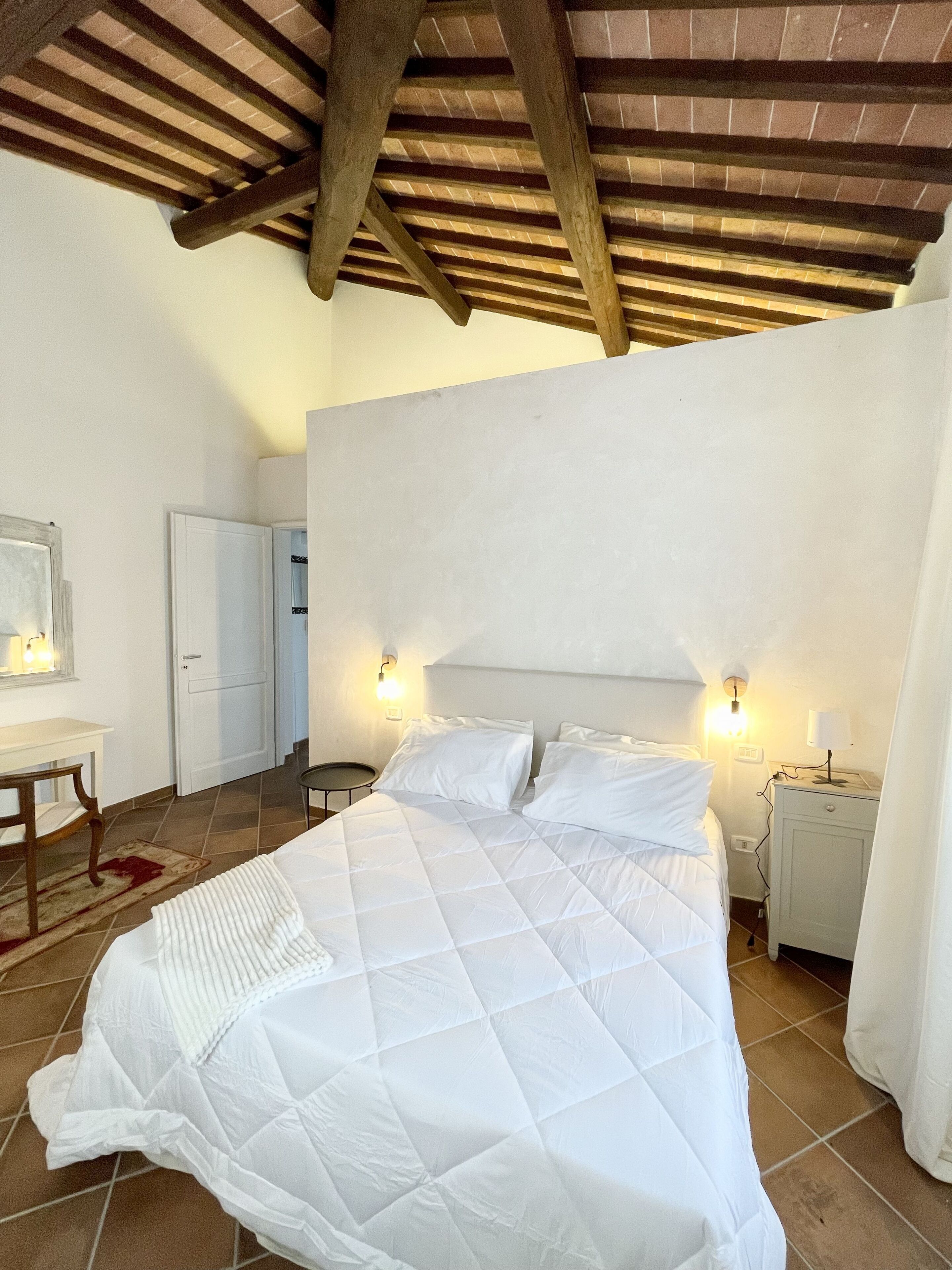 A bedroom with a large bed, a desk, and a chair.