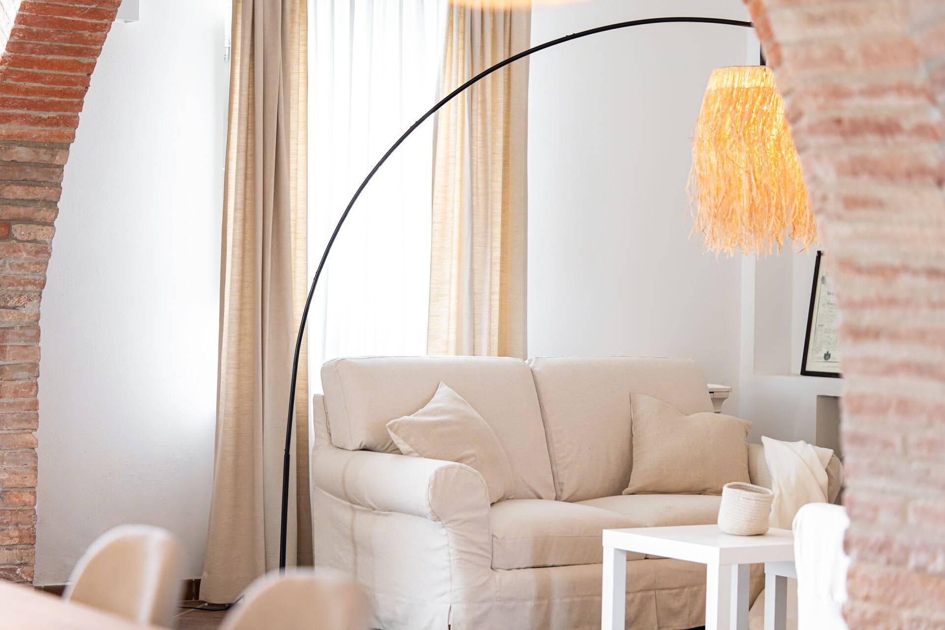 Ein modernes Wohnzimmer mit einem beigen Sofa, einem weißen Tisch und einer Stehlampe.