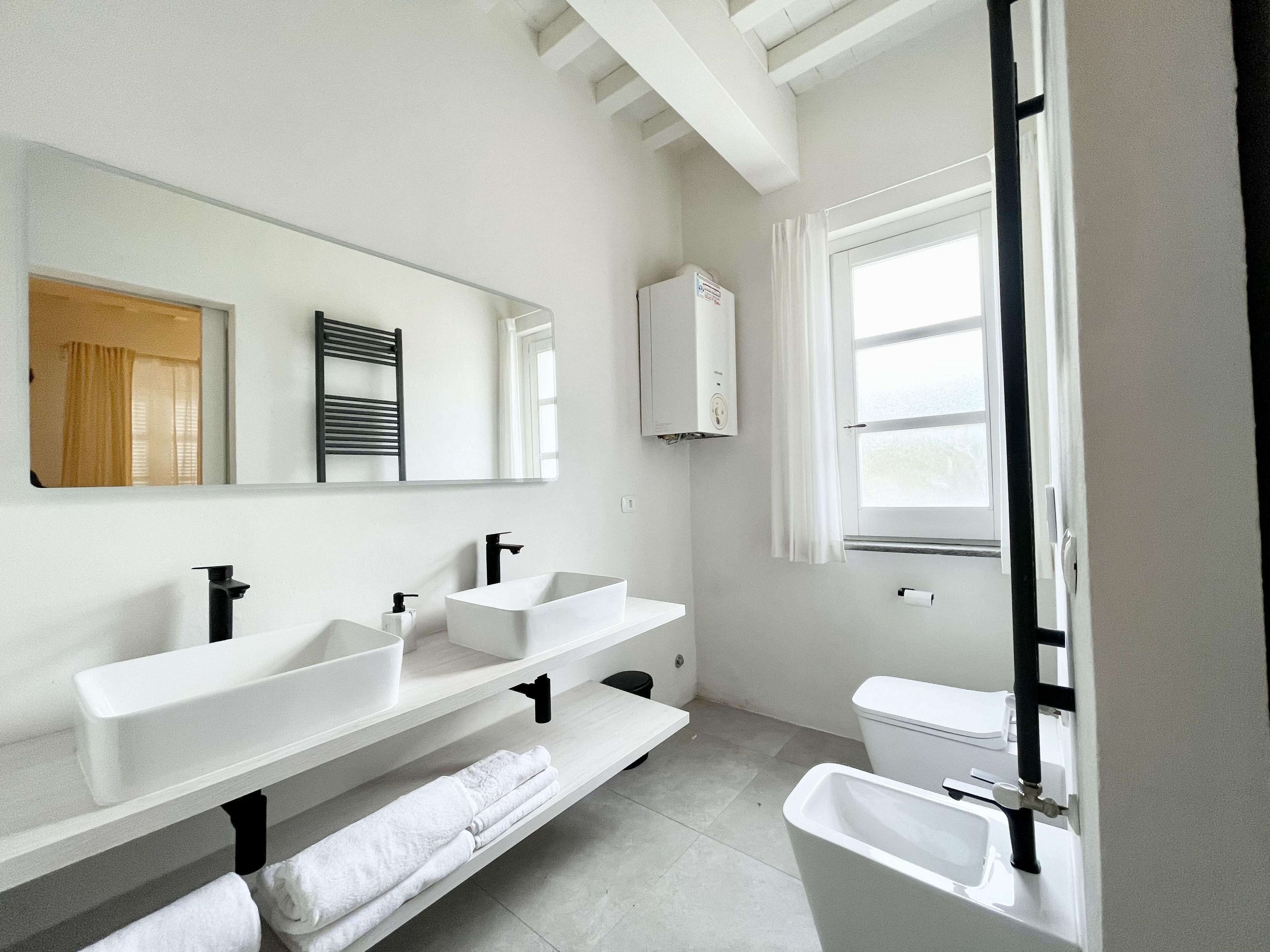 Un baño moderno con dos lavamanos, un inodoro y una ventana.