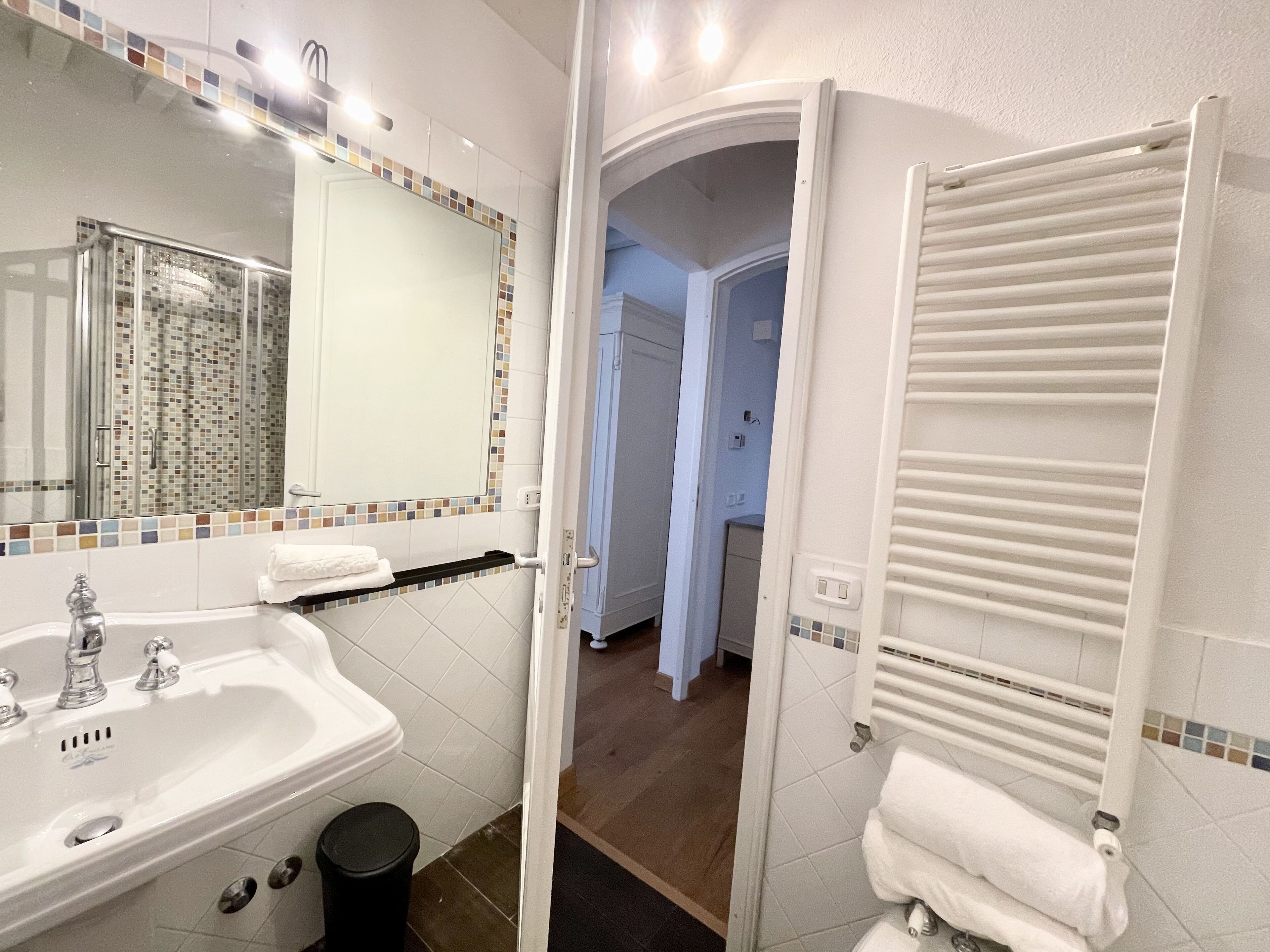 Casa de banho com lavatório branco, espelho e porta-toalhas.