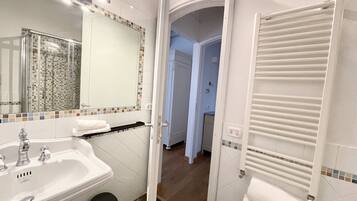 Une salle de bain avec un lavabo blanc, un miroir et un porte-serviettes.