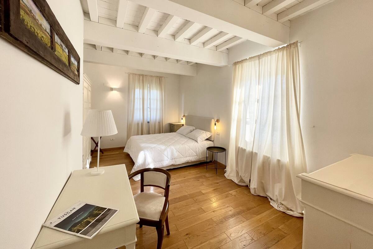 Un dormitorio con cama, escritorio, silla y mesita de noche.