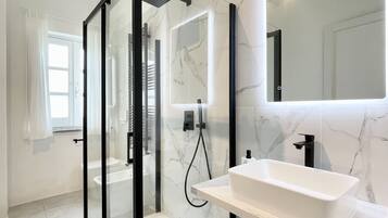 Een moderne badkamer met een douche met glazen wand, een wit wastafelmeubel en een grote spiegel.