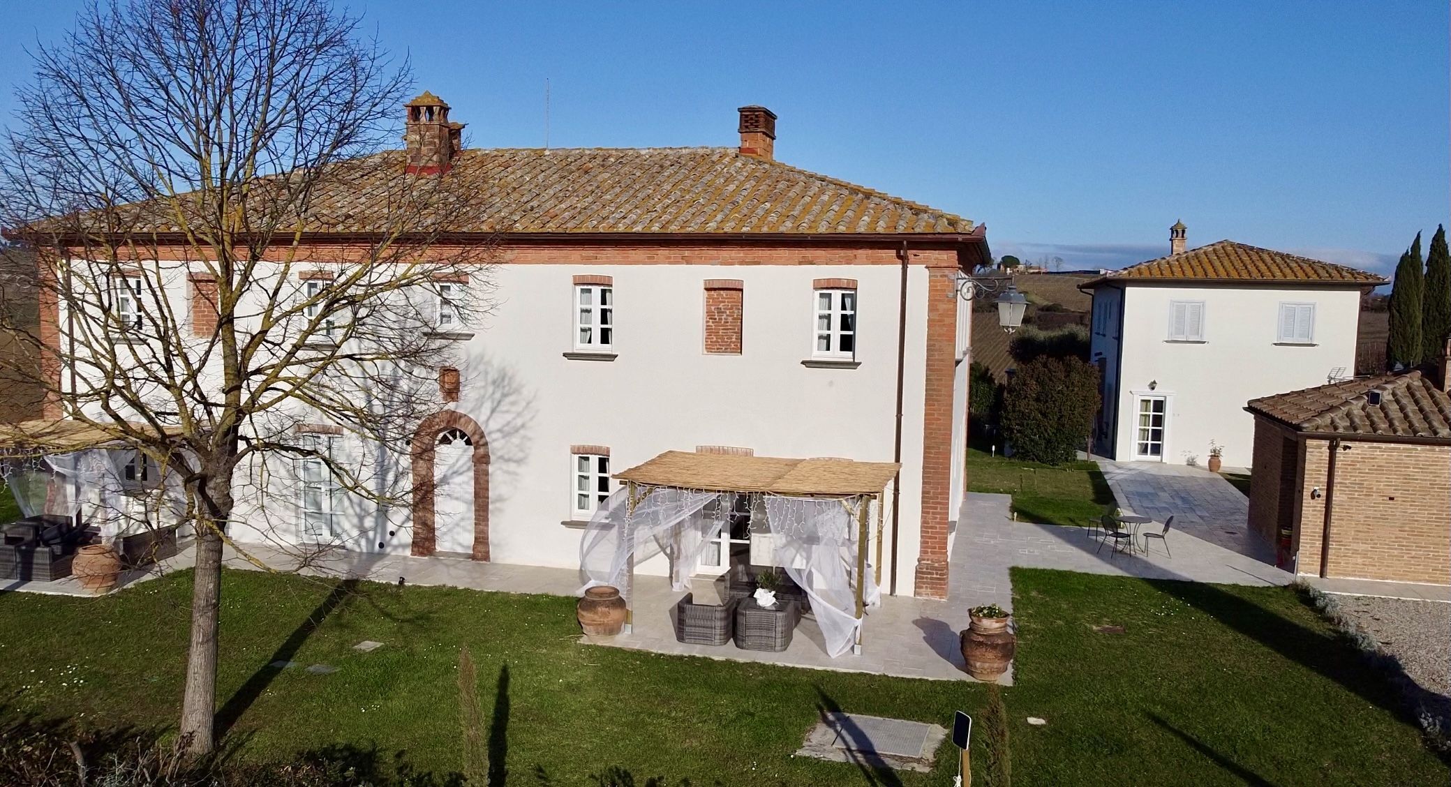 Un grande edificio bianco con tetto in tegole, una veranda coperta e un piccolo giardino.