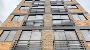 Um edifício de vários andares com fachada de tijolos, grandes janelas com grades de metal e portões de garagem pretos.