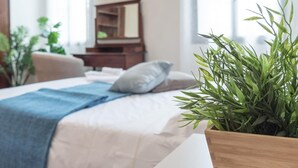 Une chambre à coucher avec un lit, une table de chevet, un miroir et une plante en pot.