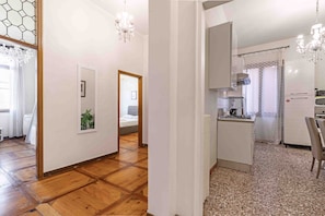 A modern interior with a wooden floor, a kitchen with a gas stove, and a dining area with a table and chairs.