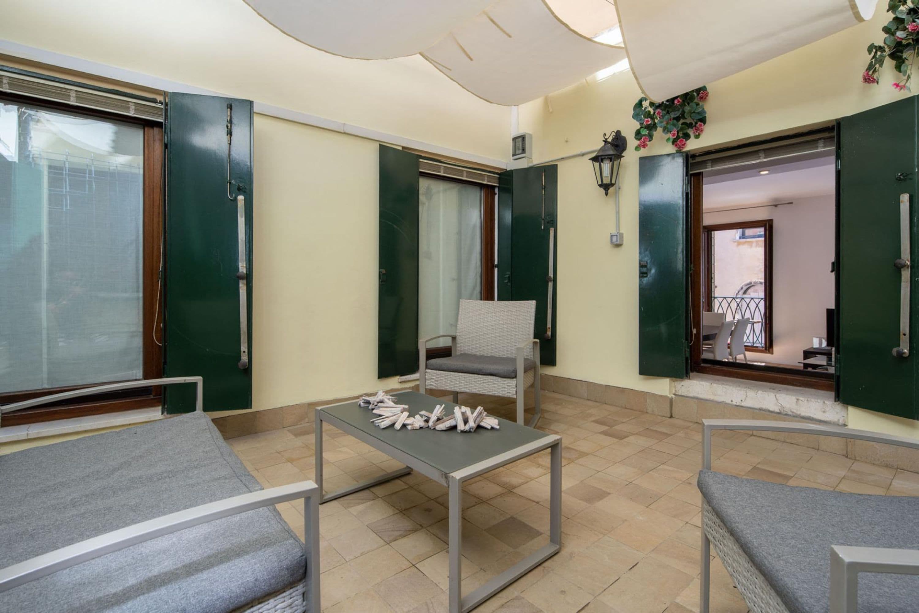 Una habitación con cama, silla, mesa y ventana.