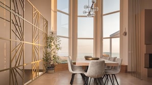 Un'area pranzo moderna con una grande finestra, un motivo geometrico al muro e un lampadario.