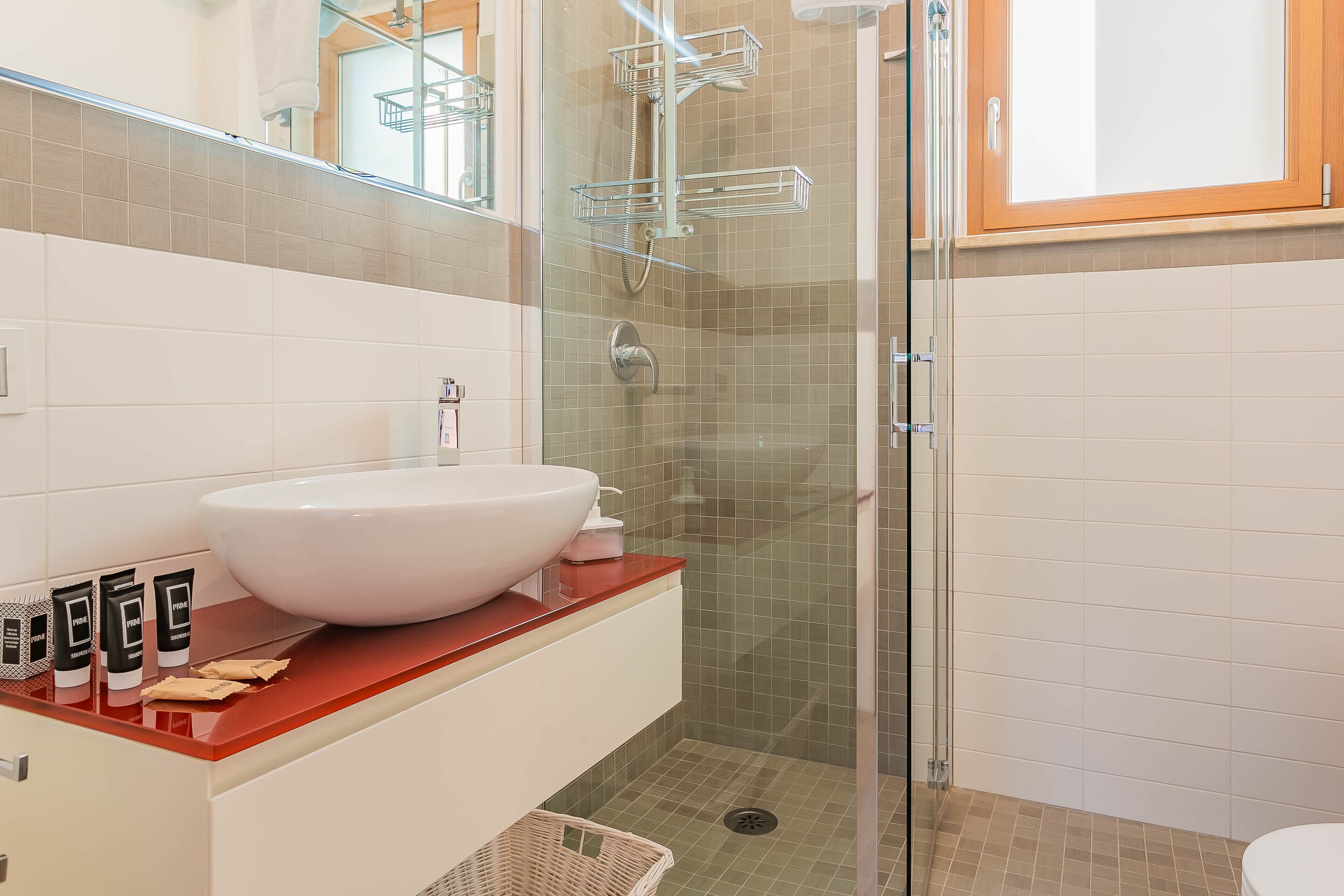 Un baño moderno con un lavabo blanco grande, una cabina de ducha de vidrio y un inodoro blanco.