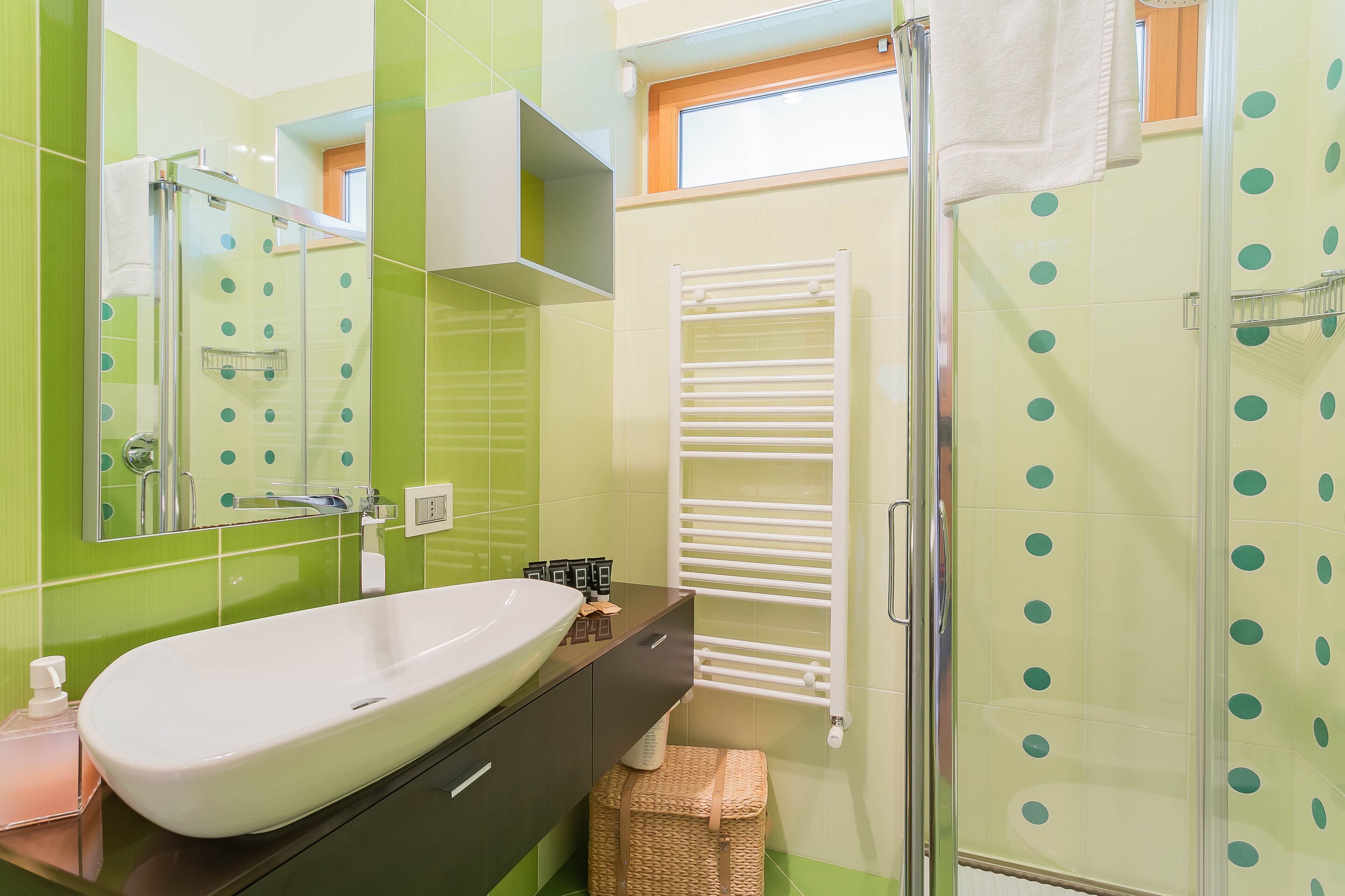 A bathroom with a large white sink, a mirror, a towel rack, and a shower area with a glass door.