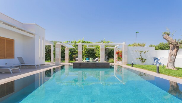 A swimming pool with a pergola and lounge chairs, surrounded by a white building and greenery. - Affittacamere Incanto nel Verde by Wonderful Italy (Polignano a Mare)