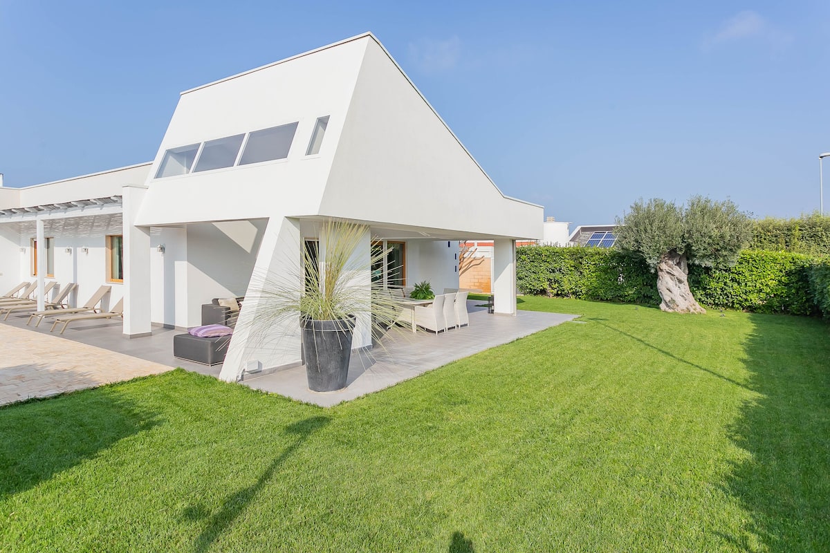 Ein modernes Haus mit Satteldach, einer Terrasse mit Gartenmöbeln und einem gepflegten Rasen.