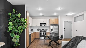 A modern kitchen with white cabinets, stainless steel appliances, and a dining area with a table and chairs. - Midnight Manor Penthouse Suite The Gulch (Nashville)
