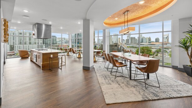 A modern hotel lobby with a large dining area, a kitchen, and large windows offering city views. - Midnight Manor Penthouse Suite The Gulch (Nashville)